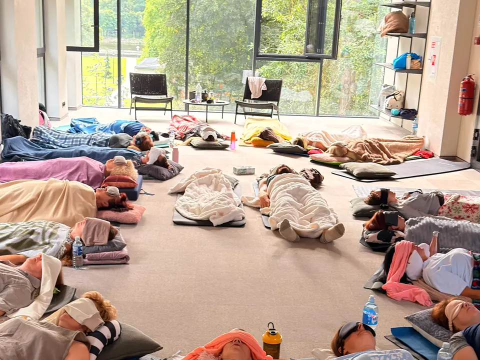 A session room: people lying down under blankets, eyes closed